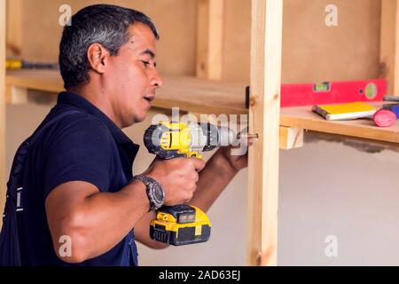 Tuttofare con cuffie giallo funziona con trapano non riparazione. Foto Stock