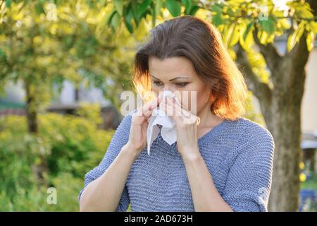 Allergie stagionali, donna con cancellazione nasale, starnuti, naso di tergitura all'aperto Foto Stock