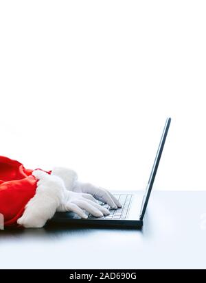 Babbo Natale utilizzando portatile su sfondo bianco. Vestito in guanti bianchi mani di Santa digitando dal computer. Foto Stock