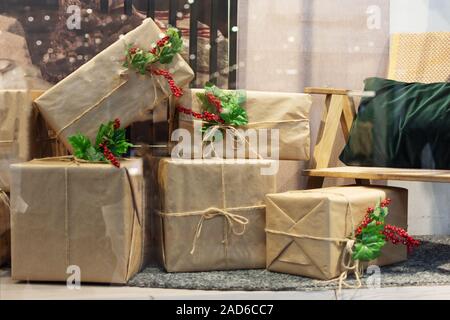 Un mucchio di grandi doni di Natale in eco la fasciatura con holly bacche. Natale o Capodanno tempo. Soggiorno con molti doni. Foto Stock