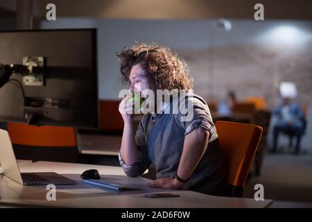 L'uomo mangiare apple nel suo ufficio Foto Stock