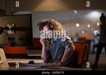 L'uomo mangiare apple nel suo ufficio Foto Stock