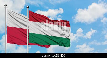 In Polonia e in Ungheria bandiera sventolare nel vento contro bianco torbido cielo blu insieme. Concetto di Diplomazia e relazioni internazionali. Foto Stock
