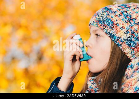 Asma ragazza paziente di inalare il farmaco per il trattamento di mancanza di respiro e respiro affannoso in un parco Foto Stock