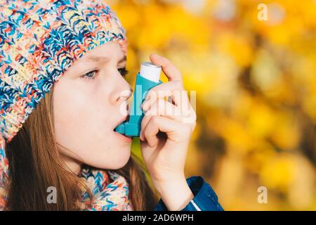 Asma ragazza paziente di inalare il farmaco per il trattamento di mancanza di respiro e respiro affannoso in un parco Foto Stock