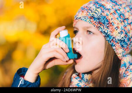 Asma ragazza paziente di inalare il farmaco per il trattamento di mancanza di respiro e respiro affannoso in un parco Foto Stock