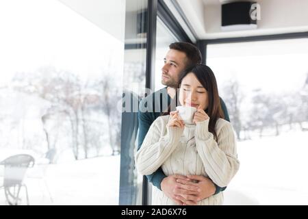 Multietnica giovane godendo il caffè del mattino dalla finestra Foto Stock