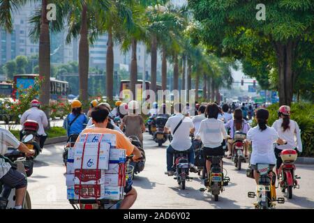 Persone il pendolarismo nelle prime ore del mattino su biciclette e scooter in una corsia separata nella città di Nanning, Guangxi, a sud ovest della Cina. Foto Stock