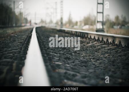 Triste triste paesaggio grigio con un vuoto che la ferrovia andando nella distanza e riflettendo il cielo bianco. Foto Stock