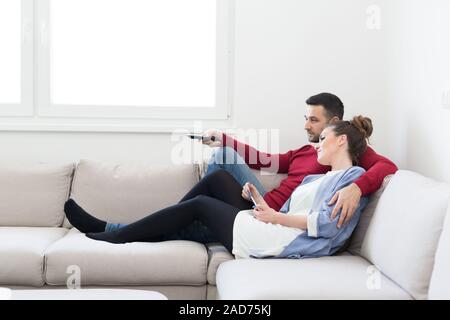 Coppia giovane sul divano guardando la televisione Foto Stock