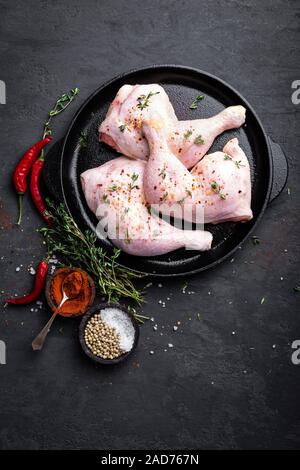 Il pollo crudo quarti, gambe in una padella su uno sfondo scuro. Vista dall'alto. Foto Stock