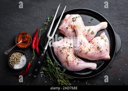 Il pollo crudo quarti, gambe in una padella su uno sfondo scuro. Vista dall'alto. Foto Stock