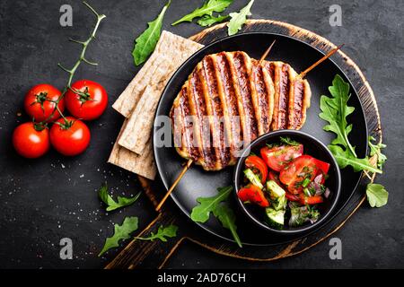 Succose grigliate di carne di pollo kebab di lula su spiedini con verdura fresca insalata su sfondo nero, vista dall'alto Foto Stock