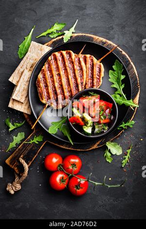 Succose grigliate di carne di pollo kebab di lula su spiedini con verdura fresca insalata su sfondo nero, vista dall'alto Foto Stock