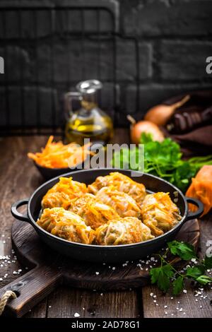 Involtini di cavolo stufato con la carne e le verdure in padella in scuro dello sfondo in legno Foto Stock