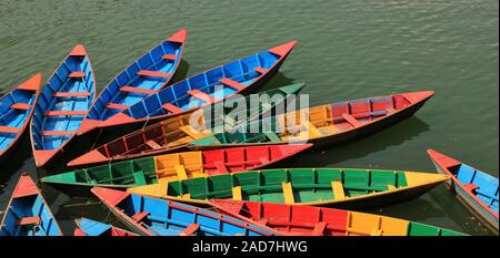 Multi legno colorate imbarcazioni a remi sul lago Fewa, Pokhara, Nepal. Foto Stock