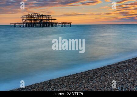 I resti del molo Ovest di Brighton visto al tramonto Foto Stock