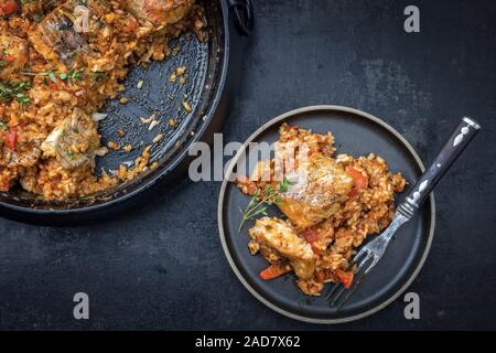 Louisiana tradizionale pesce piatto jambalaya Creola Cajun con riso e pomodori come vista in pianta in un vaso e su una piastra Foto Stock