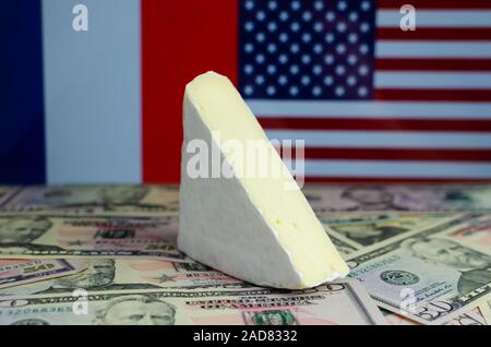 Formaggio francese Brie sulla sommità del dollaro USA le banconote e le bandiere della Francia e Stati Uniti a sfondo. Concettuale per USA e Francia guerra commerciale. Foto Stock