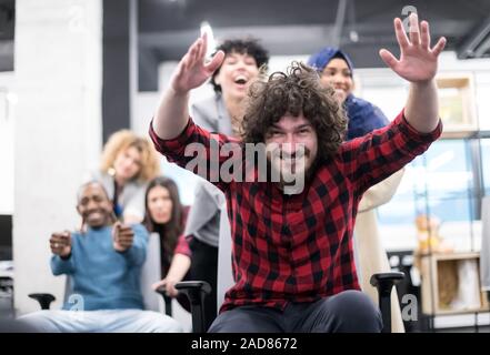 Multiethnics Business team racing su sedie da ufficio Foto Stock