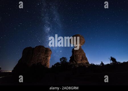 I fotografi al crepuscolo di scattare le foto alla Via Lattea dietro la roccia equilibrato, Arches National Park, STATI UNITI D'AMERICA Foto Stock