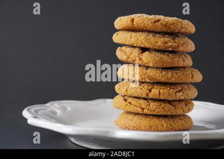 Close-up immagine di una pila di zenzero biscotti di Natale su una piastra bianca con uno sfondo nero; spazio di copia Foto Stock
