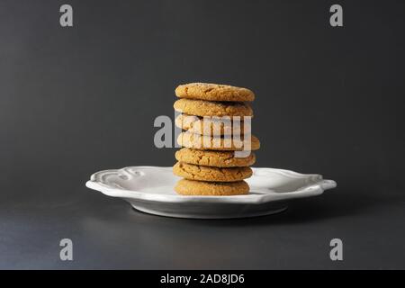 Un mucchio di fragranti biscotti di panpepato impilati in alto su una piastra bianca con uno sfondo nero; spazio di copia Foto Stock