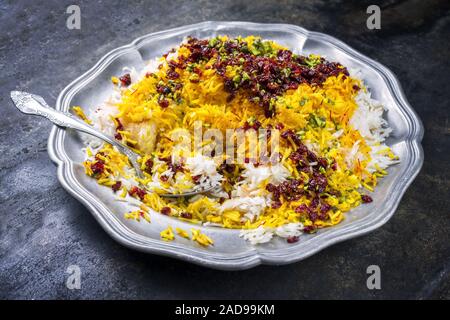 Iraniano tradizionale cotto a vapore riso allo zafferano con berberis e pistacchi come primo piano su una piastra in peltro Foto Stock