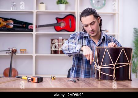 Giovane bello repairman riparazione di tamburo Foto Stock