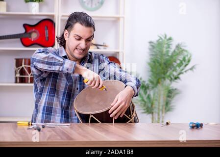 Giovane bello repairman riparazione di tamburo Foto Stock