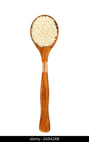 Sesamo bianco in un cucchiaio di legno su isolare. Spice sul isolare. Vista da sopra. Asciugare il condimento. Foto Stock