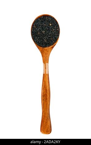 Di semi di sesamo nero in un cucchiaio di legno. Vista da sopra. Le spezie in un cucchiaio. Condimento di zucchero. Foto Stock