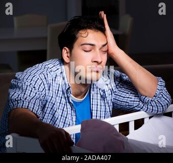 Giovane padre papà dormendo mentre guardando dopo il neonato Foto Stock