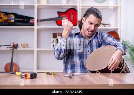 Giovane bello repairman riparazione di tamburo Foto Stock