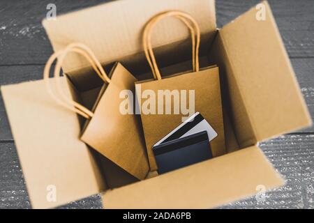 Ordini online conceptual still-life, borse per lo shopping all'interno di aprire il pacco di consegna con carte di pagamento sulla parte superiore Foto Stock