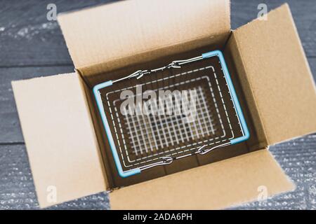 Ordini online conceptual still-life, Shopping basket all'interno di aprire il pacco di consegna Foto Stock