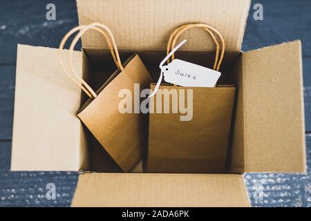 Ordini online conceptual still-life, borse per lo shopping all'interno di aprire il pacco di consegna con prezzo di vendita tag Foto Stock
