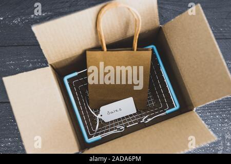 Ordini online conceptual still-life, Shopping basket all'interno di aprire il pacco di consegna con prezzo di vendita tag Foto Stock