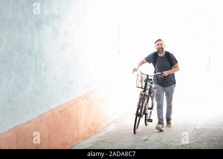 Hipster uomo con uno zaino spingendo una bicicletta retrò Foto Stock