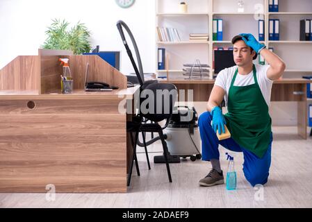 Bel giovane imprenditore pulizia ufficio Foto Stock