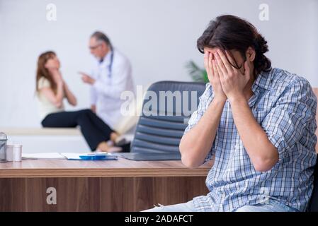 Coppia giovane visitando il vecchio medico maschio Foto Stock