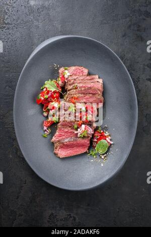 Sud tradizionale barbecue americano wagyu carne arrosto affettata con il Pico de Gallo e salsa verde guarnito come vista in pianta di un moderno Foto Stock