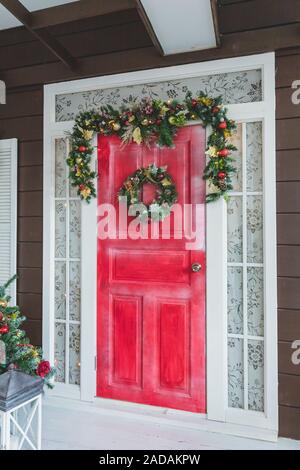 Ghirlanda di Natale con il rosso e bianco di bacche e di metallo arrugginito stelle su sfondo di legno. Caduta di neve effetto. In stile vintage. Copia dello spazio. Foto Stock