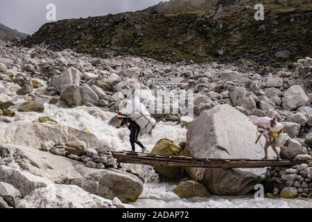 Porter trasportare carichi pesanti su un ponte su un fiume Foto Stock