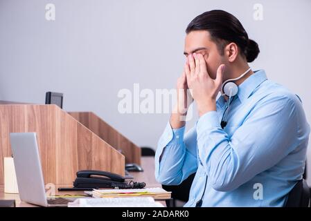 Operatore di call center al lavoro presso la sua scrivania Foto Stock