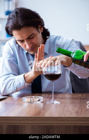 Dipendente di sesso maschile di bere alcolici e fumare sigarette a workpla Foto Stock