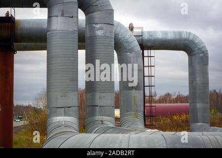 Elevata moderni tubi di calore. La pipeline al di sopra del suolo, calore di conduzione di calore della città. Linea urbana in isolamento metallico nel quartiere residenziale della città. Foto Stock