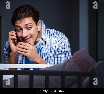 La felice papà alla ricerca dopo il neonato di notte Foto Stock