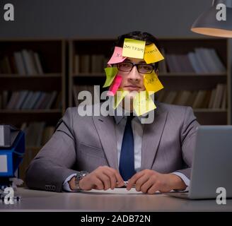 Uomo d'affari che soggiornano in ritardo per ordinare le priorità Foto Stock