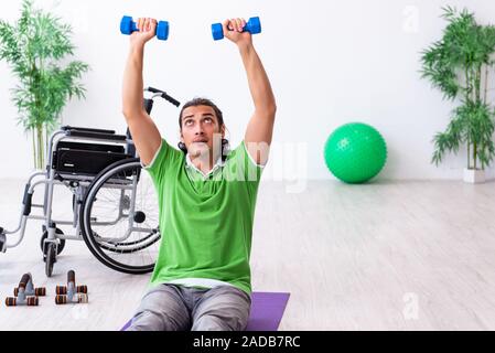 Giovane uomo in carrozzella facendo esercizi in ambienti interni Foto Stock